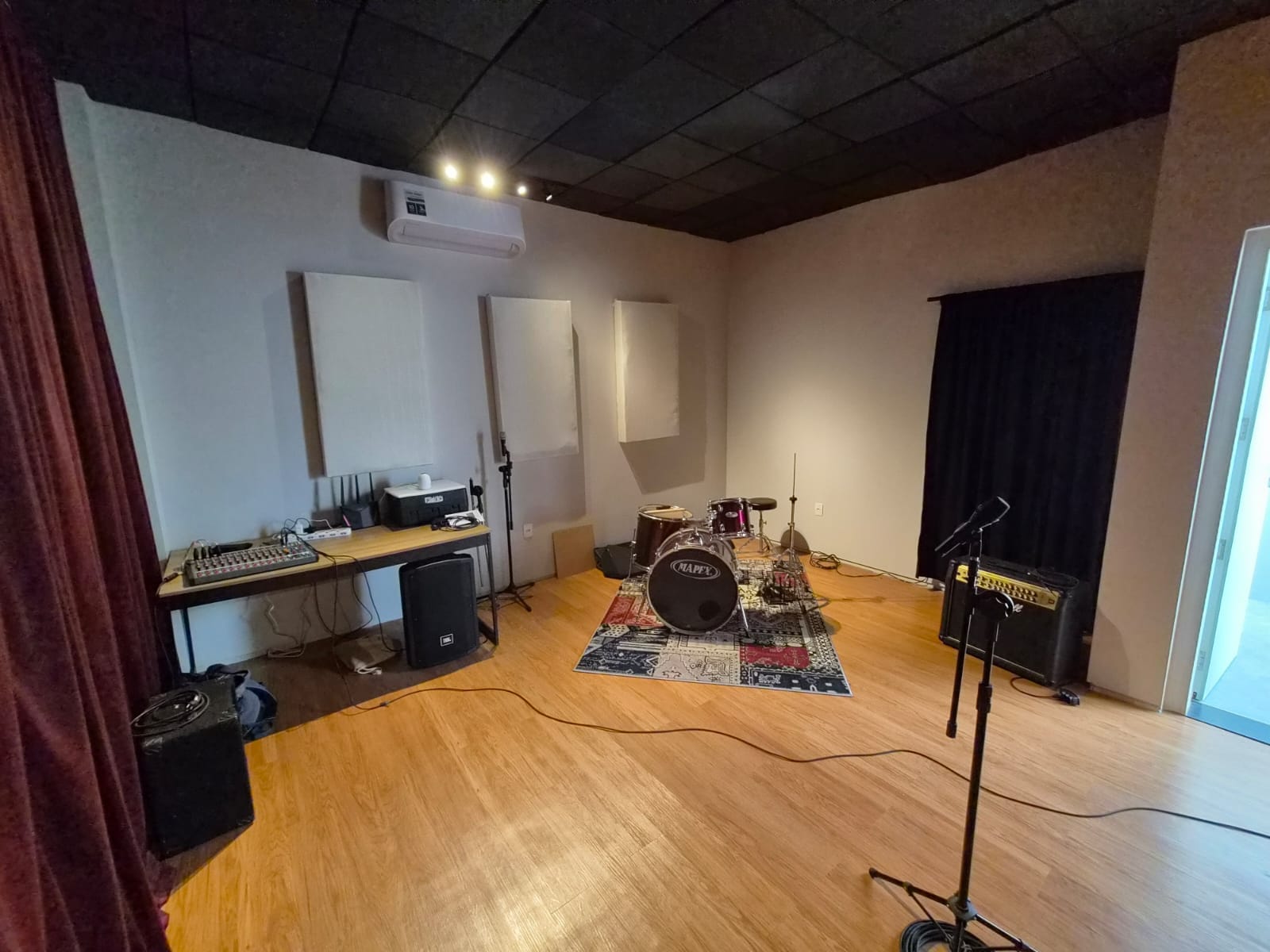 Estúdio musical com bateria, mesa de som, caixas e painéis acústicos