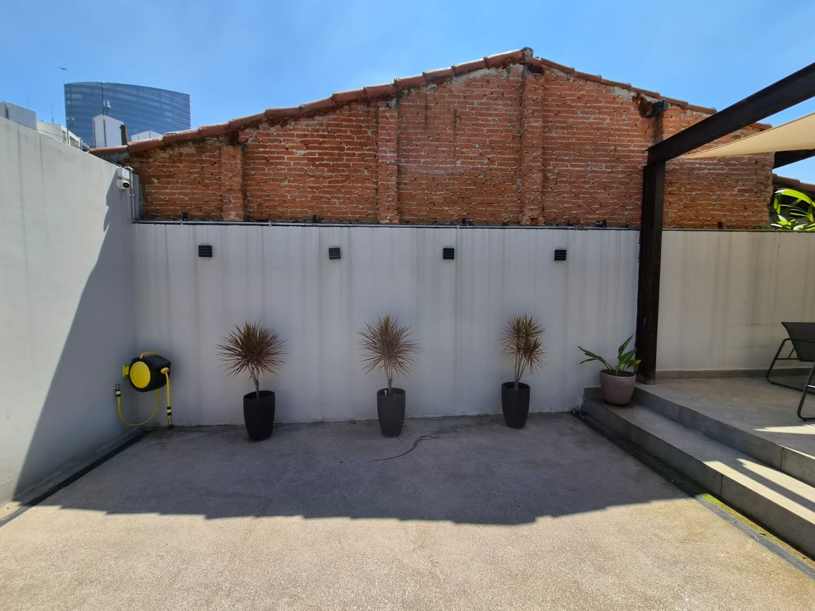 Muro de tijolos aparentes com vasos de plantas no pátio