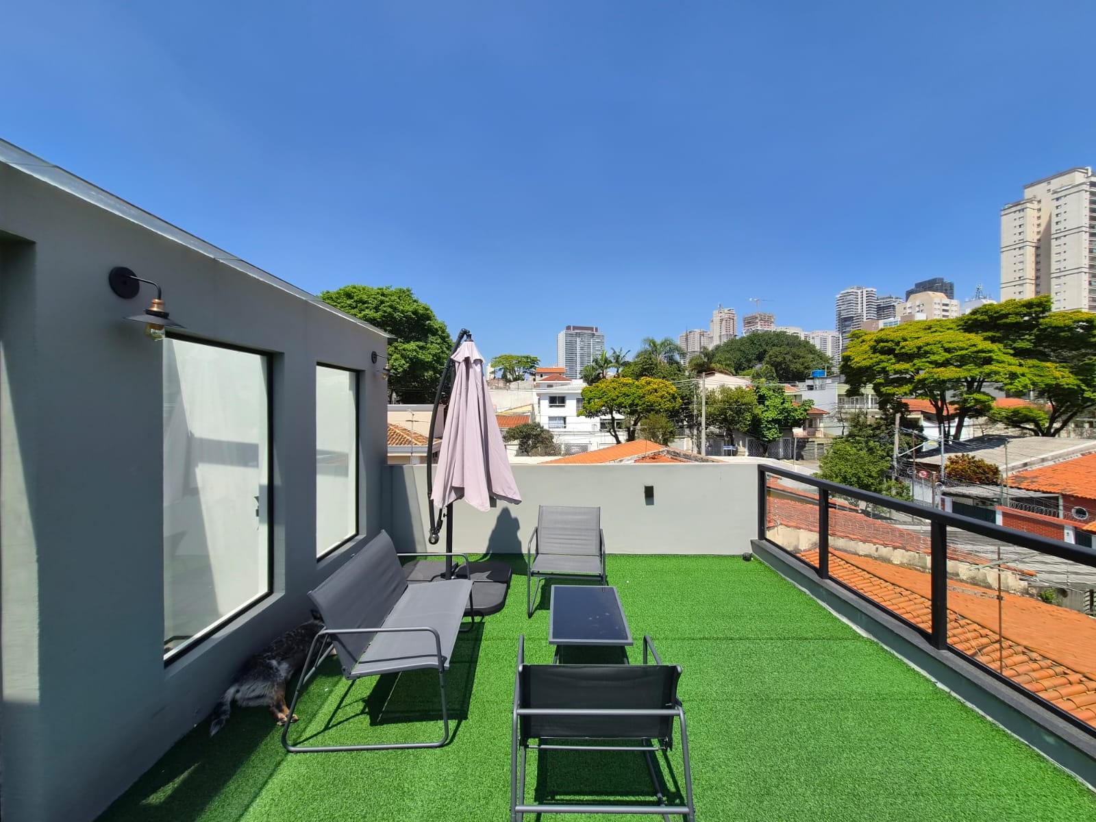 Terraço com guarda-sol, cadeiras e vista para a cidade